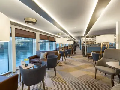 Die helle Bar-Lounge an Bord der MS Antonia zeigt moderne Möbel, warme Beleuchtung und große Fenster mit Blick auf das Wasser.