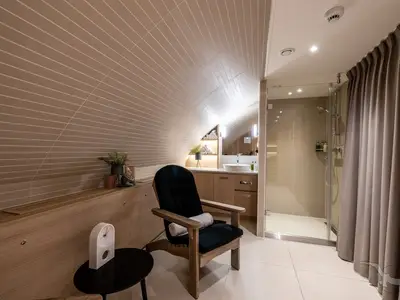 Innenansicht eines modernen Spa-Wellness-Bereichs oder Luxusbadezimmers an Bord der MS Antonia mit Holzmöbeln, einer begehbaren Dusche und einem Waschtisch unter einer schrägen Decke.