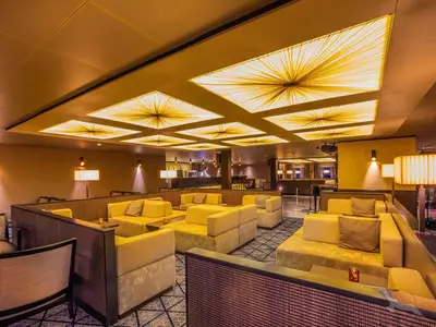 Blick in die gemütliche Casablanca Bar an Bord der MS Artania mit goldenen Deckenleuchten. Elegante, gelbe Sitzgruppen und eine Bar im Hintergrund schaffen eine warme Atmosphäre.