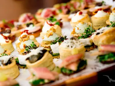 Eine Nahaufnahme zeigt eine reichhaltige Auswahl eleganter Canapés und kleiner Gebäckstücke, appetitlich angerichtet für ein Buffet an Bord der MS Asara.