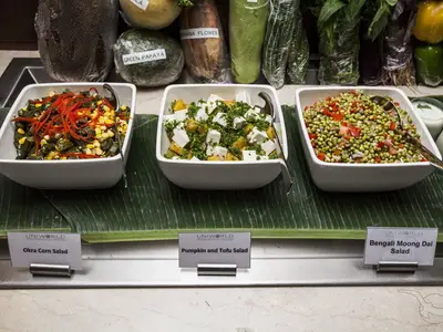 Salatbuffet an Bord der MS Ganges Voyager. Drei Salatschüsseln: Okra Corn, Kürbis-Tofu und Bengali Moong Dal. Auf Bananenblättern angerichtet und beschriftet.