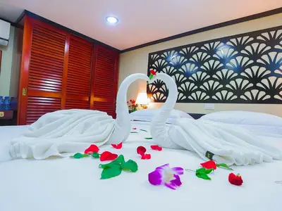 Romantisch geschmückte Außenkabine der MS Lan Diep. Auf dem Bett sind zwei Handtuch-Schwäne, Rosenblätter und eine Orchidee. Hinten Holzschränke und eine gemusterte Wand.