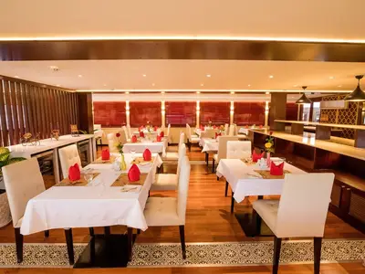 Blick in das geräumige Restaurant an Bord der MS Lan Diep mit zahlreichen, weiß gedeckten Tischen und roten Servietten. Warme Beleuchtung und Holzelemente schaffen eine gemütliche Atmosphäre. Ohne Personen.