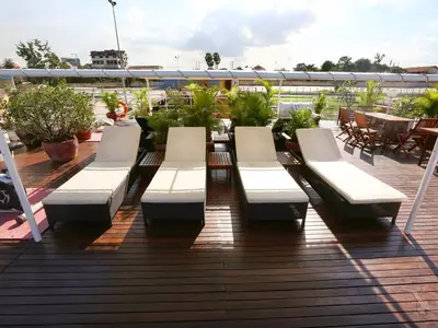 Das Sonnendeck der MS Lan Diep mit vier Liegestühlen, Beistelltischen und vielen Topfpflanzen auf dunklem Holzdeck. Eine entspannte Atmosphäre unter hellem Tageslicht.