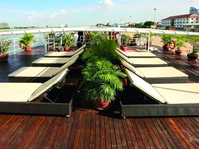 Sonnendeck der MS Lan Diep mit Liegestühlen und Topfpflanzen. Im Hintergrund sind Meer und Stadtkulisse zu erkennen.
