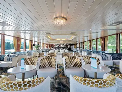 Die helle und geräumige Panorama-Lounge an Bord der MS Rhein Prinzessin. Elegante Sessel, Tische und große Fenster bieten Blick auf die Flusslandschaft.