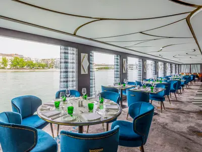 Das stilvolle Restaurant "Waterside" der Riverside Debussy bietet blaue Samtsessel, elegant gedeckte Tische und einen Panoramablick auf den vorbeiziehenden Fluss.