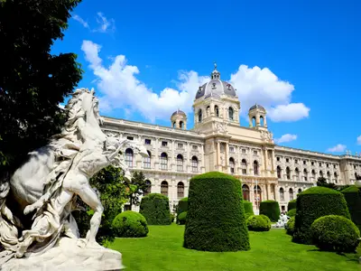 Das prachtvolle Kunsthistorische Museum in Wien mit einer beeindruckenden Reiterstatue, üppigen Gärten unter blauem Himmel. Eine Sehenswürdigkeit auf der Route der Riverside Mozart.
