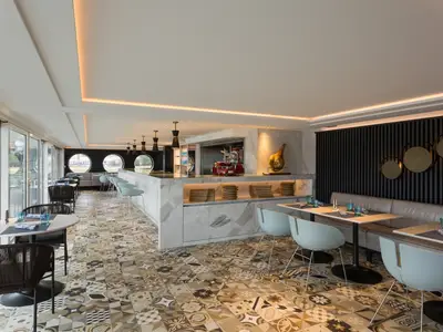 Ein modernes Restaurant 'Blue Deli' an Bord der Riverside Mozart mit offener Kueche, Bar und verschiedenen Sitzbereichen. Grosse Fenster bieten eine helle Atmosphaere und Blick nach draussen.