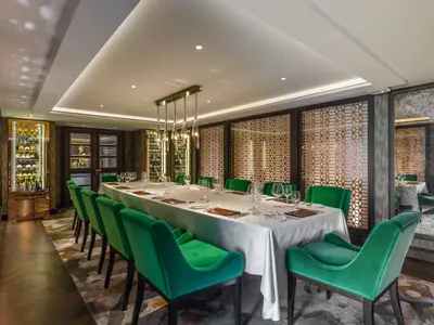 Der luxuriöse Vintage Room an Bord der Riverside Mozart. Langer, weiss gedeckter Tisch mit smaragdgrünen Samtstühlen. Beleuchtete Weinkühlschränke und goldene Gittermuster zieren die Wände.