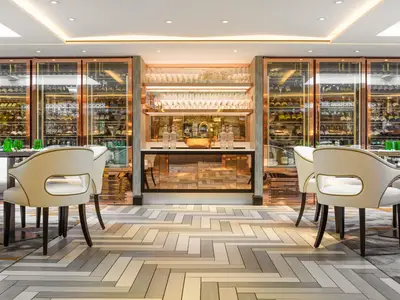Elegantes Restaurant an Bord der Riverside Mozart. Helle Stühle, grüne Gläser, beleuchtete Weinkühlschränke und eine Bar prägen den Raum.