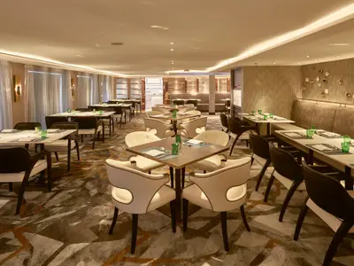 Elegantes Restaurant an Bord der Riverside Mozart. Gedeckte Tische, komfortable Stühle. Warme Beleuchtung und moderne Einrichtung.
