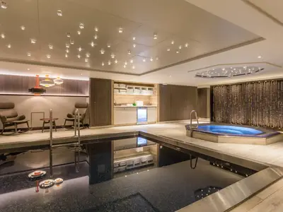 Ein luxuriöser Spa-Bereich an Bord der Riverside Mozart mit Innenpool, Whirlpool, Ruhesesseln und einer Theke. Elegante Beleuchtung.