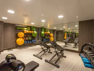 Fitnessstudio der Riverside Mozart. Helle, moderne Einrichtung mit Übungsbällen, Hanteln, Bänken und Spiegelwand. Gut beleuchtet, ohne Personen.