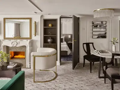 Ein luxuriöses Wohnzimmer in einer Owner's Suite an Bord der Riverside Mozart. Es gibt einen Kamin, einen Esstisch und eine offene Tür zu einem Schlafzimmer.