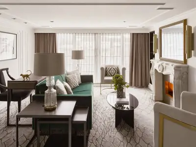 Gemütlicher Wohnbereich einer luxuriösen Suite an Bord der Riverside Mozart. Ein grünes Sofa, ein Glastisch, ein Kaminsims und große Fenster sind zu sehen.