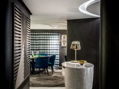 Das luxuriöse Restaurant an Bord der Riverside Ravel zeigt tiefblaue Samtstühle an einem gedeckten Tisch, eine goldene Lampe auf einem Beistelltisch und dunkle Holzpaneele. Ein elegantes Ambiente.