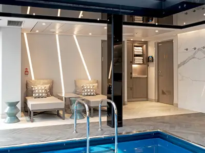 SPA-Bereich der Riverside Ravel: helle Liegesessel, Beistelltische, Schränke mit Handtüchern und Marmorwand. Pool-Haltegriffe im Vordergrund sichtbar.