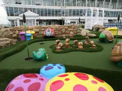 Blick auf eine farbenfrohe Minigolfanlage an Deck der Allure of the Seas, umgeben von künstlichem Fels und dekoriert mit Tier- und Pilzfiguren.