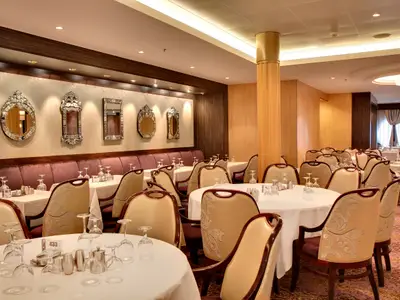 Hauptrestaurant der Allure of the Seas: Elegante Einrichtung mit gedeckten Tischen, hellen Stühlen und dekorativen Wandspiegeln.