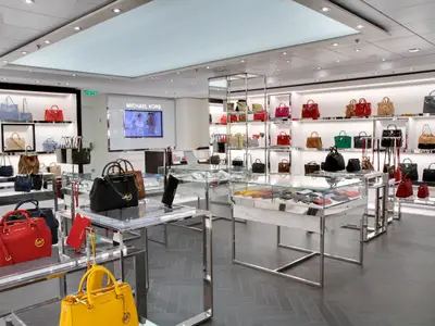 Ein heller Michael Kors Laden an Bord der Allure of the Seas, gefüllt mit einer Vielzahl von farbigen Handtaschen, Geldbörsen und Schmuckstücken, präsentiert auf eleganten Verkaufsdisplays.