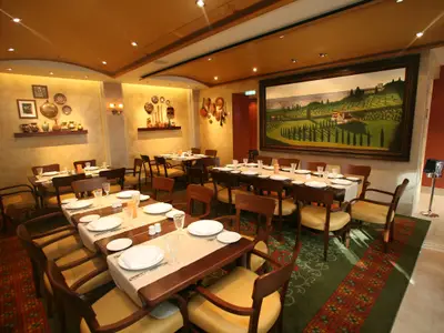 Restaurantbereich auf der Allure of the Seas. Gedeckte Tische, Holzstühle, grüner Teppich. Wände mit rustikaler Deko und großem Landschaftsgemälde.