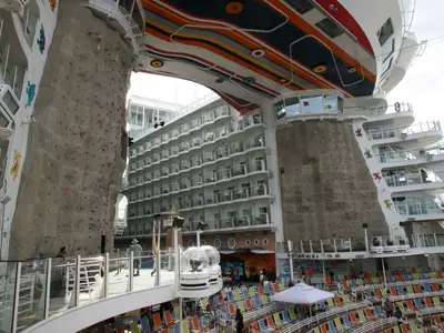 Nahansicht der Allure of the Seas: Zwei Kletterwände, umgeben von Kabinenbalkonen, einem Pooldeck und einer auffällig bemalten Deckenstruktur.