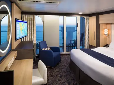 Helle Balkonkabine der Anthem of the Seas mit Doppelbett, Sessel, Schreibtisch und Balkon mit Meerblick.