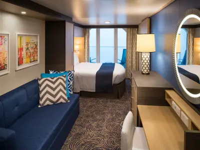 Innenansicht einer Balkonkabine auf der Anthem of the Seas mit Bett, Sofa, Schreibtisch und Blick auf das Meer.
