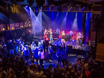 Ein Panoramablick auf die Music Hall an Bord der Anthem of the Seas, wo eine Live-Band auf der Bühne spielt und viele Gäste tanzen.