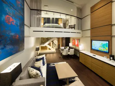 Elegante zweistöckige Loft-Suite der Anthem of the Seas. Unten: Wohnzimmer, Esstisch, TV-Bereich. Oben: Schlafzimmer mit Doppelbett, Glasgeländer.