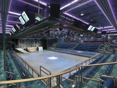 Eisshow-Arena 'Studio B' der Explorer of the Seas. Eisfläche, umgeben von leeren Sitzreihen. Bühnenbeleuchtung und Technik über der Arena. Bereit für Shows.