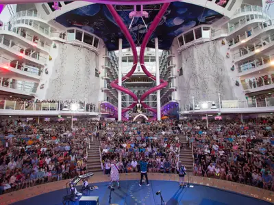 Im AquaTheater der Harmony of the Seas performen Künstler vor Publikum. Kletterwände und pinke Ultimate Abyss Rutschen zwischen den Schiffsdecks.