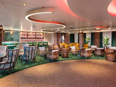 Innenansicht der Icon of the Seas Bar-Lounge: Grüne Theke, beleuchtete Regale, Sessel auf grünem Teppich, Fliesenboden. Geschwungene Decke mit roten Akzenten.