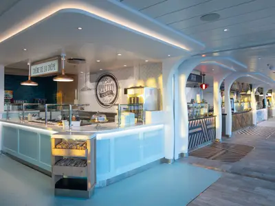 Der moderne Buffetbereich der Icon of the Seas. Helle Theken, eine Crêpe-Station, diverse Essensausgaben und gemusterte Böden prägen den stilvollen Raum.