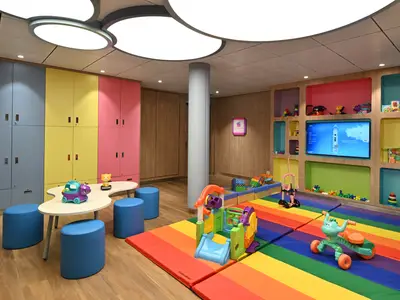 Ein bunter Spielbereich auf der Icon of the Seas. Es gibt Schließfächer, einen Spieltisch, Regale voller Spielzeug, einen TV und Regenbogenmatten mit Spielgeräten.