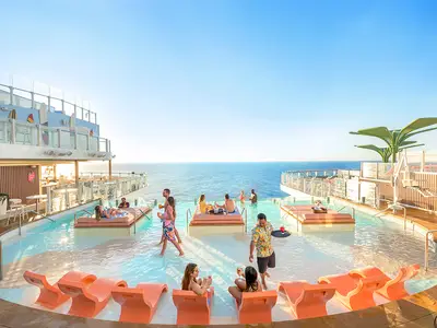 Der Poolbereich auf der Icon of the Seas zeigt entspannte Gäste in flachen Becken und auf Liegen. Ein Kellner serviert Drinks. Im Hintergrund erstreckt sich das offene Meer.