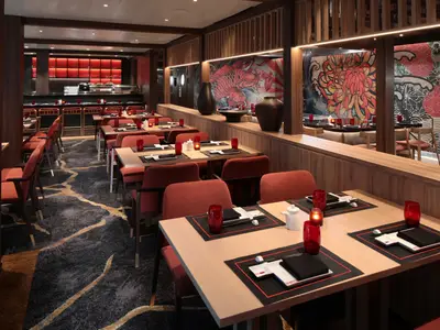 Blick in ein japanisches Spezialitätenrestaurant mit vielen Tischen, roten Stühlen, Holzvertäfelung und detailreichen Wandmalereien von Koi und Blumen.