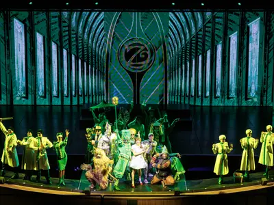 Bühnenshow des 'Zauberer von Oz' auf der Icon of the Seas. Darsteller in grünen Kostümen und als bekannte Charaktere stehen vor einer beleuchteten Smaragdstadtkulisse.