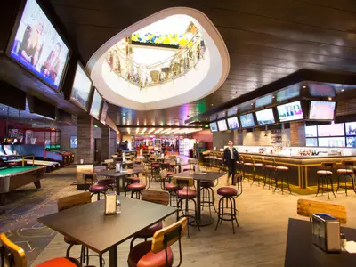 Independence of the Seas: Sportsbar mit TV, Spielhalle Billard, Essplätze. Eine Person. Atrium mit Ballons oben.