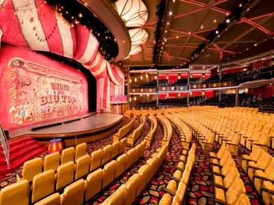 Theater der Independence of the Seas. Eine bunte Zirkus-Bühne mit 'Under the Big Top' Deko und leere gelbe Sitze im Saal und auf den Rängen.