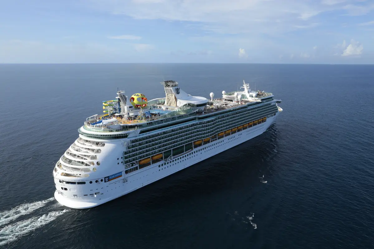 Eine Vogelperspektive zeigt die weiße Mariner of the Seas von Royal Caribbean auf dem weiten, blauen Meer. Auf dem Oberdeck sind bunte Wasserrutschen, eine gelbe Kugel und weitere Freizeitbereiche zu erkennen. Der Himmel ist hellblau mit einigen Wolken.
