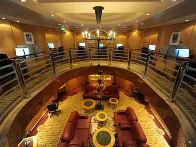 Innenansicht der Mariner of the Seas. Oben ein Internetcafé, unten eine Lounge mit roten Sofas und Tischen. Eine Skulptur hängt von oben.