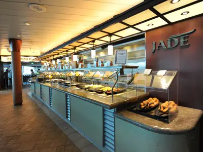 Innenansicht des Buffet-Restaurants Jade auf der Mariner of the Seas. Eine lange Theke zeigt diverse Speisen. Im Vordergrund sind frische Brötchen zu sehen.