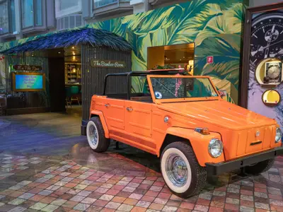 Ein orangefarbener Wagen auf der Navigator of the Seas, neben der "The Bamboo Room"-Bar und einer Uhrenausstellung.