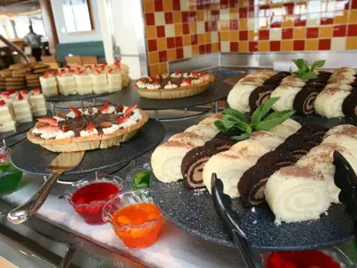 Dessertbuffet auf der Oasis of the Seas: Kuchen, Tartes mit Erdbeeren und Nüssen, helle und dunkle Rollkuchen, mit Minze garniert. Dazu bunte Gelee-Desserts.