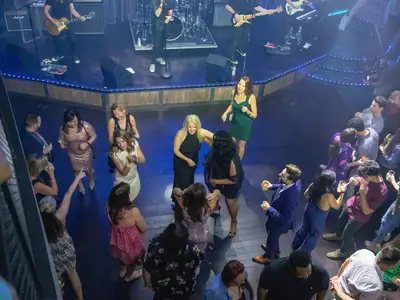 Gäste tanzen und feiern auf der blauen Tanzfläche eines Clubs an Bord der Oasis of the Seas. Eine Band spielt live. Lebhafte Abendstimmung.