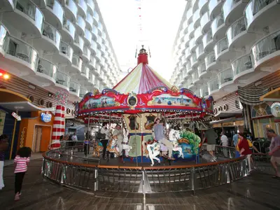 Ein Karussell auf dem Boardwalk der Oasis of the Seas, umgeben von Passagieren und den charakteristischen Balkonkabinen.