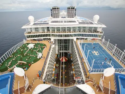 Hoher Blick auf das Heck der Oasis of the Seas. Zu sehen sind ein Minigolfplatz, ein Basketballfeld und eine offene Promenade mit Spielbereich.