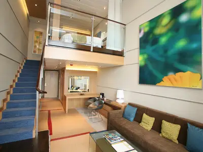 Innenansicht einer zweistöckigen Loft-Kabine auf der Oasis of the Seas. Unten: Wohnbereich mit Sofa und Schreibtisch; oben: Schlafzimmer, verbunden durch eine Treppe.